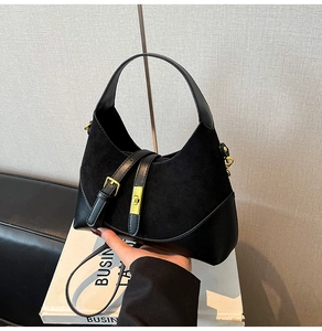 Detail of black half-moon handbag featuring mixed suede and leather with gold hardware buckle