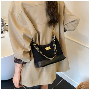 Detail of black quilted shoulder bag featuring chunky gold chain strap and turn-lock
