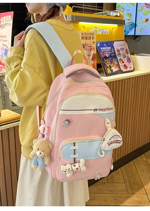 Detailed view of pink school backpack with cute plush charms and embroidered logo