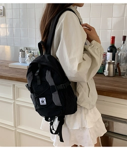 Close-up of black nylon backpack side pocket with gray honeycomb texture and adjustable cords