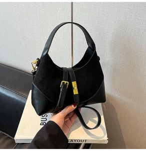 Detail of black contrast handbag with suede leather stitching and golden buckle closure