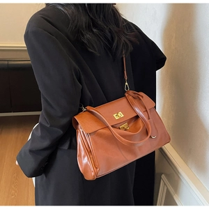 Detail of caramel faux leather tote with golden twist lock on black blazer