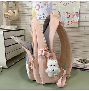 Detailed view of the pink student backpack showing internal storage and cute plush charm