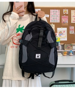 Detailed view of black nylon backpack with elastic cord and penguin logo patch