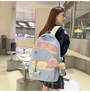 Detail of color-block nylon backpack with heart badges and cute plush animal charms