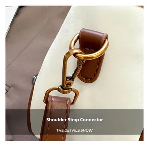 Detail of brown leather strap with bronze metal D-ring and clasp on cream bucket bag