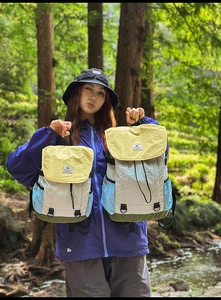 Outdoor view showing two sizes of color-block nylon backpacks with yellow flaps in nature