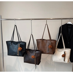 Row of minimalist large-capacity leather tote bags with cute plush bear charms in four colors