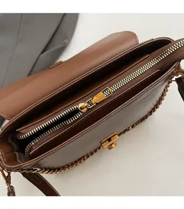 Gros plan sur la fermeture éclair en métal doré et la structure interne du sac marron