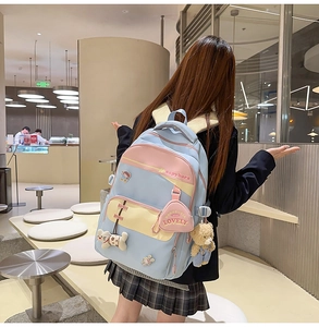 Close-up of blue and pink school backpack with capybara print and cute plush pendants