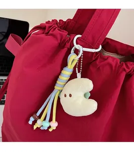 Detail eines Plüschmond-Anhängers mit buntem Seil und Perlen an einer roten Tasche