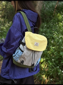 Detail of color-block nylon backpack featuring drawstring closure and forest outdoor setting