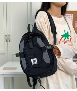 Detail of black tactical nylon backpack with crisscross elastic cords and logo label