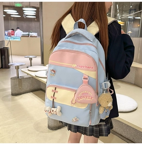 Detail of color-blocked student backpack featuring cute cartoon charms and plush bear accessories