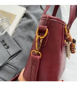 Detailaufnahme burgunderrote Beuteltasche mit Vintage-Goldbeschlägen und Perlen