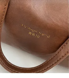 Detail of brown lychee grain leather tote with gold Fashion Trend logo engraving