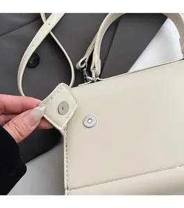 Close-up of cream leather shoulder bag showing magnetic flap closure and neat stitching