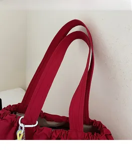 Nahaufnahme einer roten Nylontasche mit breitem Schultergurt und buntem Anhänger-Zubehör