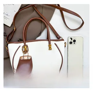 Size comparison of a beige hobo bucket bag with brown leather trim and a smartphone