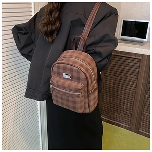 Détail d'un sac à dos en nylon à carreaux marron avec double fermeture et poignée