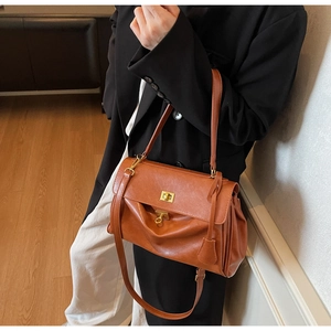 Close-up of caramel brown vintage tote bag with gold twist lock and flap detail