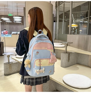 Detail of light blue student backpack with colorful pockets and cute cartoon charms