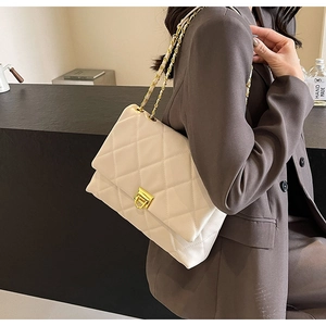Detail der cremefarbenen Stepptasche mit goldenem Kettenriemen und metallischem Schloss