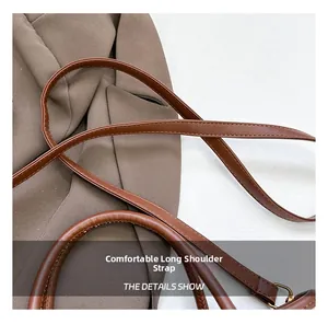 Detail view of brown faux leather shoulder bag showing the strap texture and handle stitching