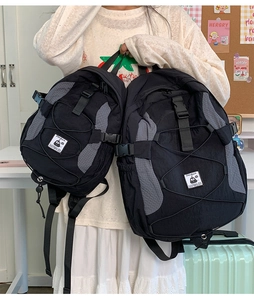 Detail of black nylon backpack featuring front bungee cord system and side buckle straps