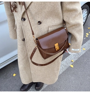 Détail du sac bandoulière vintage marron foncé avec chaîne dorée et fermoir chic