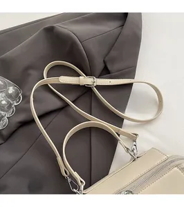 Detail of adjustable cream faux leather strap and neat stitching on fashion handbag