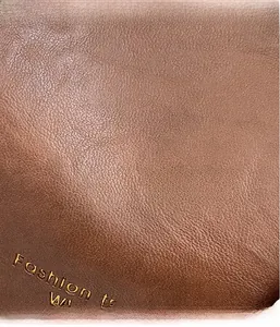 Close-up of brown lychee texture leather with golden Fashion lettering on a tote bag