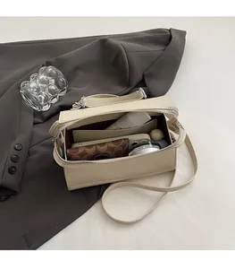 Top-down view of open cream box handbag showing interior capacity for phone and cosmetics