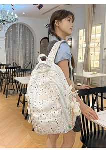 Detail of star-print backpack featuring multiple pockets and a plush doll pendant