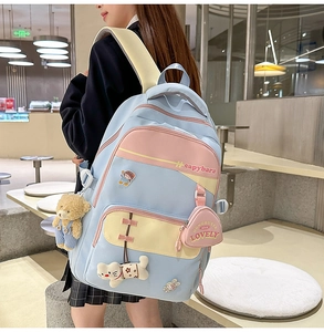 Detail of cute backpack with capybara embroidery and plush animal charms on pink straps
