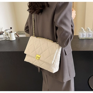 Nahaufnahme der cremefarbenen Stepptasche mit goldener Kette und Metalldrehverschluss