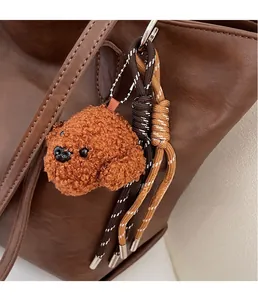 Detail of cute brown teddy bear plush charm hanging on a stylish leather shoulder bag