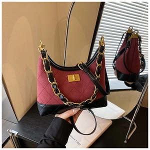 Detail of burgundy quilted shoulder bag with gold chain strap and metallic twist lock