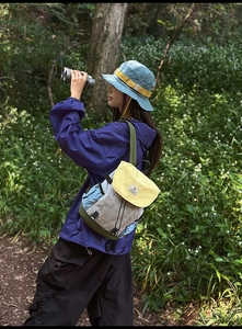 Outdoor leisure backpack with color-blocking design and matching hat in a forest setting