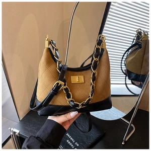 Macro detail of brown quilted suede bag with gold chain and black leather trim