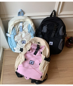 Three lightweight nylon backpacks in blue, black and pink with elastic front bungee cords