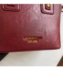 Detailansicht der weinroten Leder-Eimertasche mit goldener Logo-Prägung