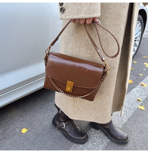 Détail du sac à rabat en cuir marron foncé avec chaîne dorée et boucle carrée vintage