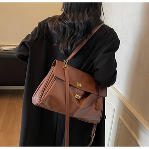 Detail of dark brown leather tote bag with gold metal twist lock and matte texture