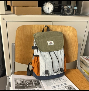 Close-up of retro color-block nylon backpack featuring drawstring and buckle on a wooden chair
