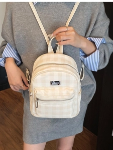 Mini sac à dos beige à carreaux en similicuir porté par un mannequin en style décontracté