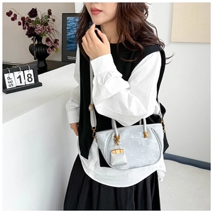 Chic light gray bucket bag with gold hardware shown on model in a stylish commute setting
