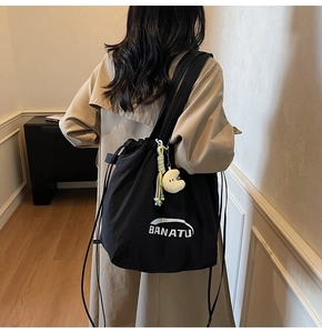 Detail der schwarzen Nylon-Tasche mit BANATU-Logo und gelbem Mond-Plüschanhänger