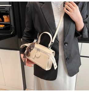Cream square crossbody handbag with matte leather finish and woven side charm decoration