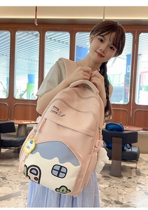 Detail of pink school backpack with house embroidery and soft plush ball charm